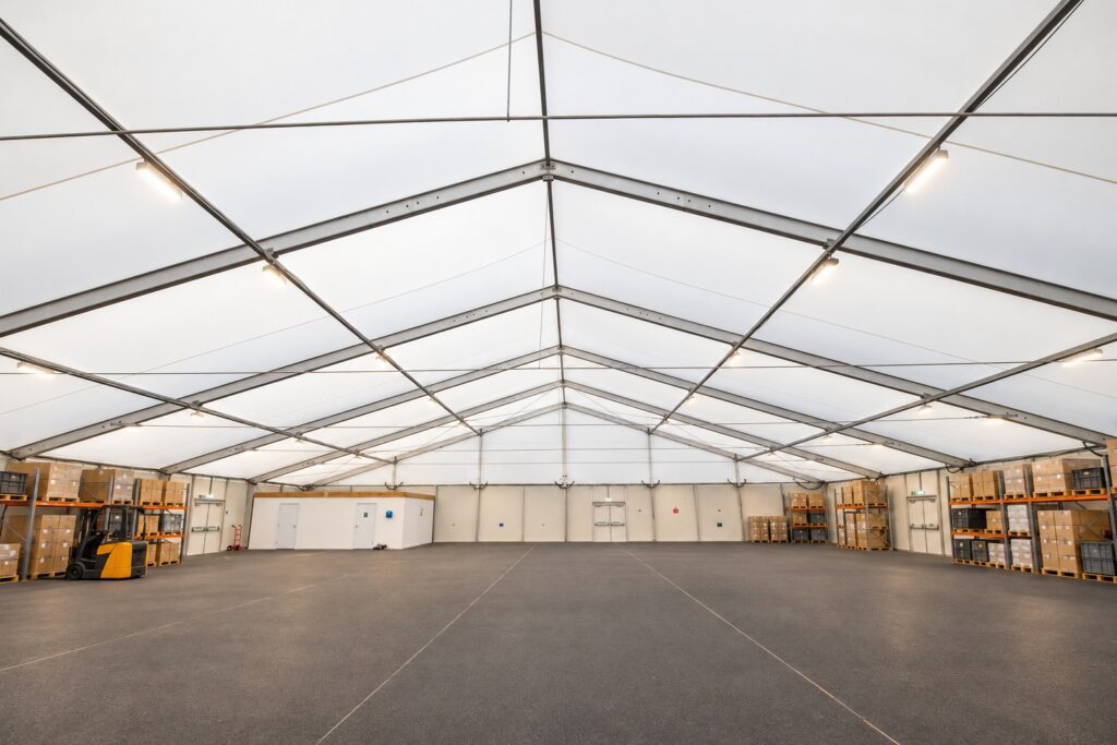 Temporary warehouse marquee interior with pallet racking, soft lighting and a forklift